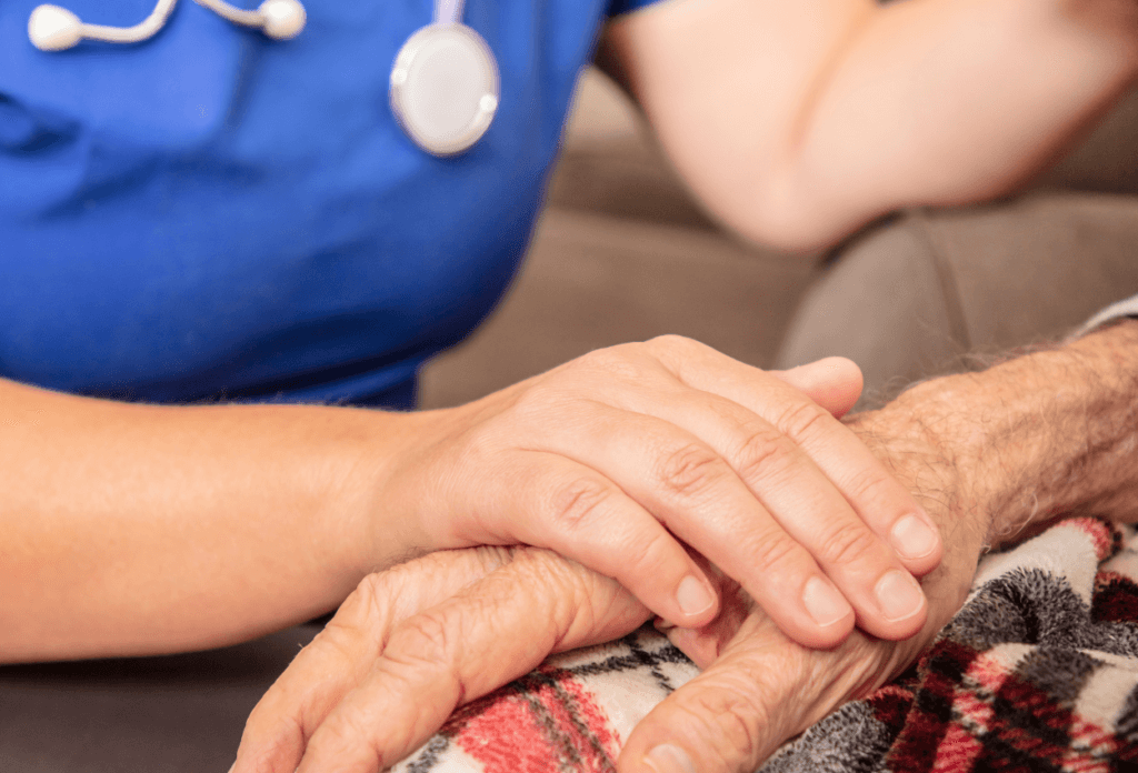 A picture of a nursing home nurse holding the hand of a patient