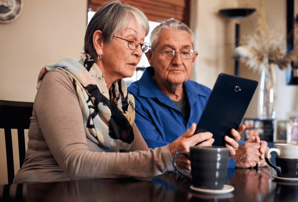 A picture of two elderly people looking at an iPad.