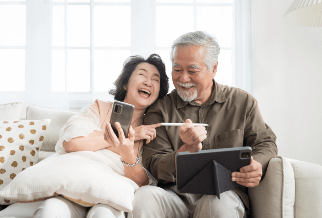 A picture of a senior couple on their phones together laughing.