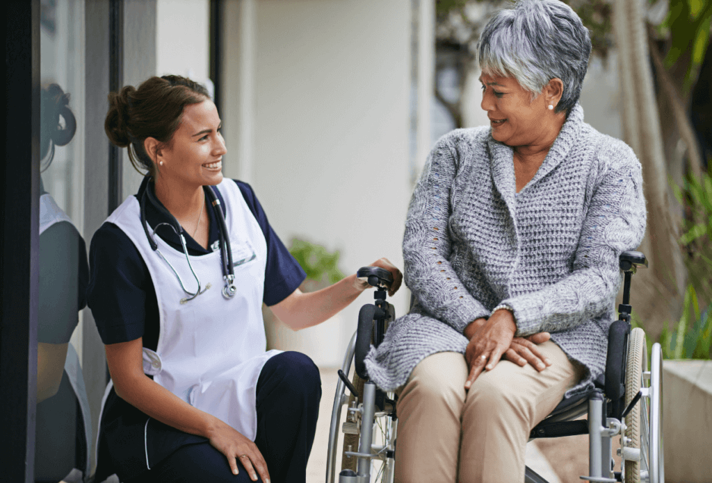 A nurse sitting with a senior citizen sitting in a wheelchair