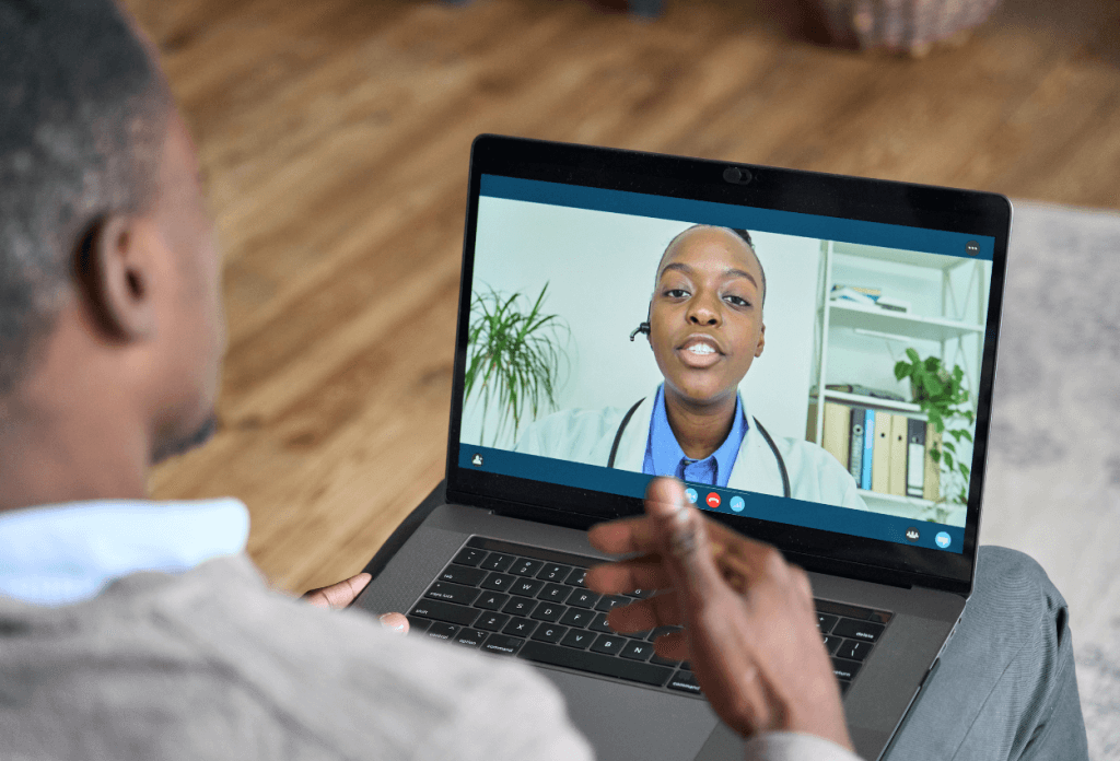 A picture of a man in a telehealth appointment talking to a doctor on his laptop.