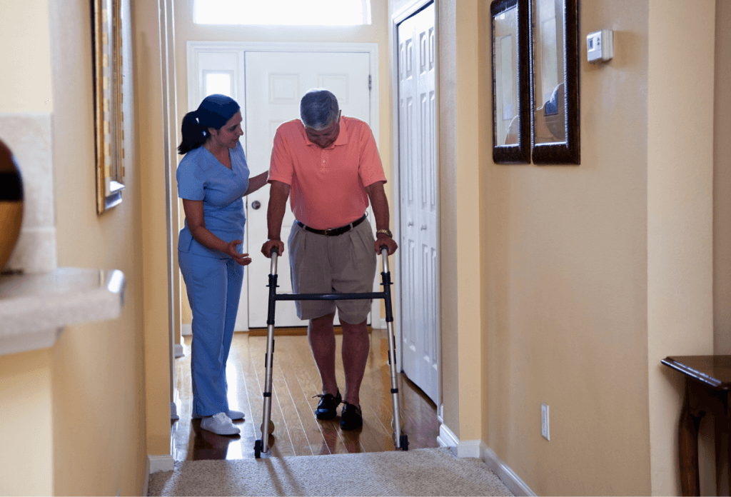 A female nurse is helping a senior male patient walk with walker down the hall in a blog titled "Understanding Medicare for Chronic Illness: A Senior’s Path to Better Health."