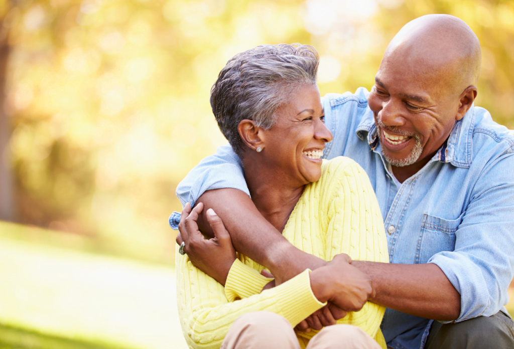 A smiling senior citizen couple embracing outside.