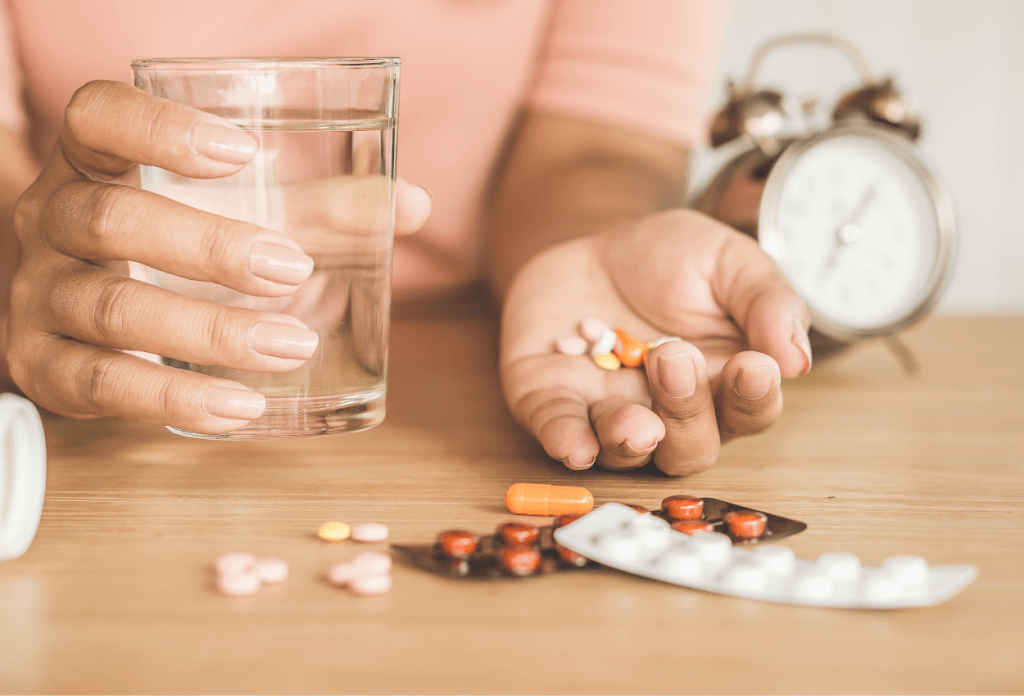 Image shows someone talking their medications with a glass of water.