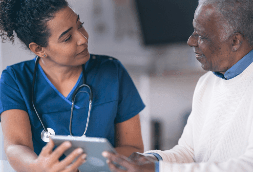 A male senior patient is speaking with a female nurse about chronic illness and Medicare coverage.
