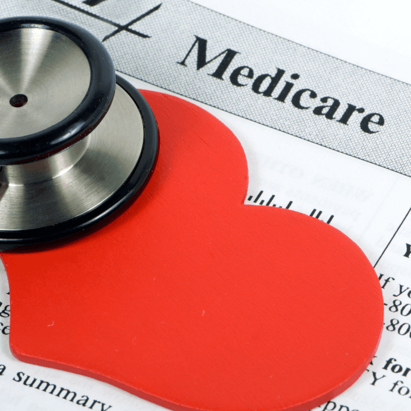 A photo of a stethoscope and a Medicare card partially covered by a red heart cutout.