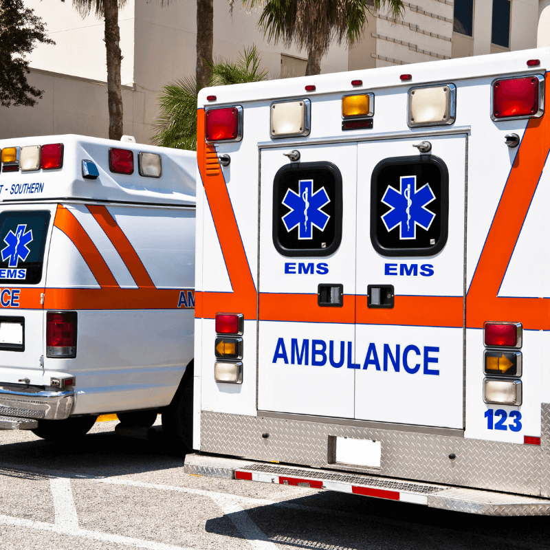 A picture of the back of two ambulances parked in a parking lot.